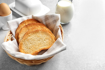Wicker basket with tasty toasted bread on table