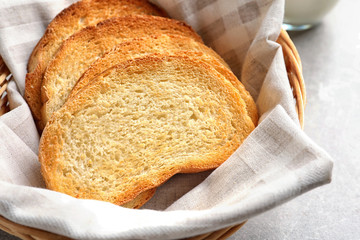 Wicker basket with tasty toasted bread on table