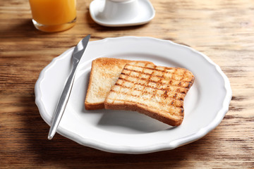 Plate with toasted bread on table