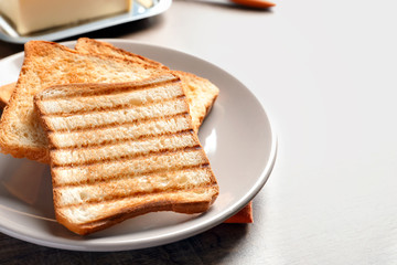 Plate with toasted bread on table