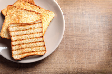 Plate with toasted bread on table