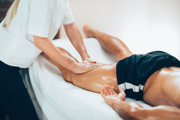Leg massage. Physical therapyst massaging leg of young male athelete