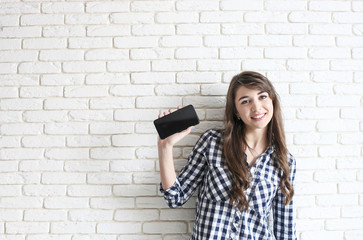 Happy millennial girl having fun indoors. Portrait of young beautiful woman with perfect teeth smile, brown eyes. Minimalistic interior, white brick textured wall background, loft style. Copy space.