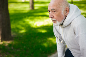 Elderly man running in green park, copy space