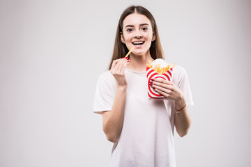 Harmful food, woman eating french fries, woman eating, woman on isolated gray background. Health concept.