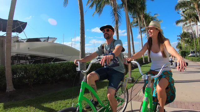 Couple of tourists riding bike on Miami waterfront promenade