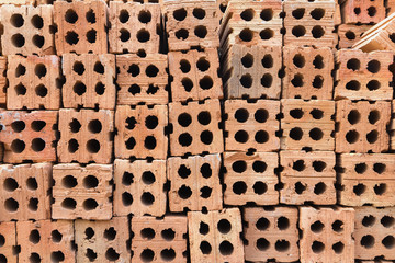 Stacks of hard orange-brown bricks block, a building construction material.