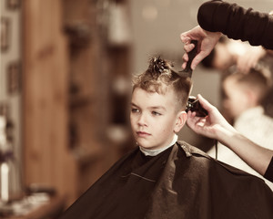 Handsome boy getting his hair and beard cut at barber shop