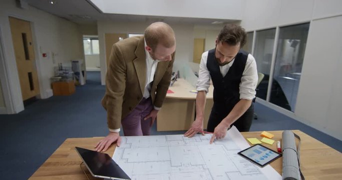 4K 2 Architects in a planning meeting with their colleagues working in background. Slow motion.