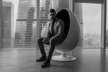 Business man sitting in a chair in a modern office.