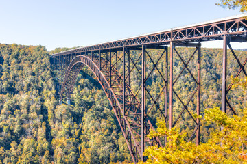 Overlook of West Virginia green mountains in autumn fall at New River Gorge Bridge with closeup of metal structure and golden foliage