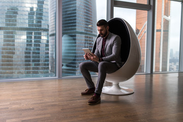 Business man sitting in a chair in a modern office.