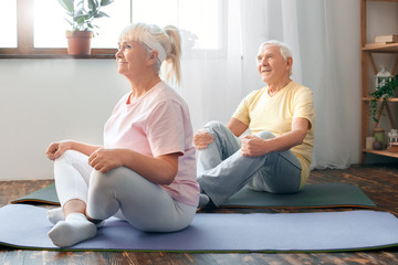 Senior couple doing yoga together at home health care butterfly pose stretching