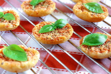 Close up of Mini pizas baked with tomato, oregano and basil on red and white checkered table coth