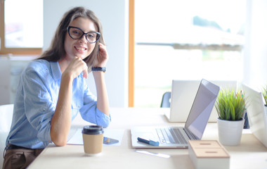 Obraz premium Young woman sitting in office table, looking at laptop computer screen . Young woman