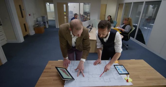 4K Portrait serious architects or engineers working on a project together. Slow motion.