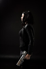 portrait of black haired girl wearing leather clothes, moody lighting on black background.