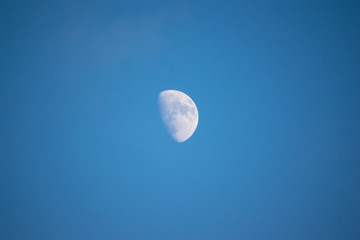 Blue moon on the light blue day sky