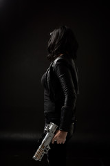 portrait of black haired girl wearing leather clothes, moody lighting on black background.