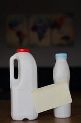 Plastic bottles with paper sticker without text  standing on the wooden table at home in the daylight with blurred map of planet Earth on the background