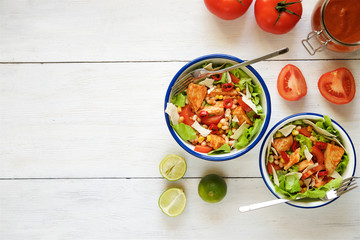 BBQ chicken salad with tomatoes, beans, corn and chips. Light wooden background
