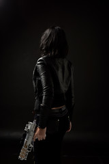 portrait of black haired girl wearing leather clothes, moody lighting on black background.