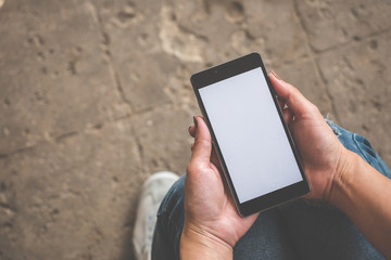 Hand holding black mobile smart phone with blank white screen at outdoor to checking e-mail or social network. technology and lifestyle concept.
