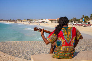 Fototapeta premium Muzyk z gitarą i włosami rasta na plaży Santa Maria na Sal na Wyspach Zielonego Przylądka