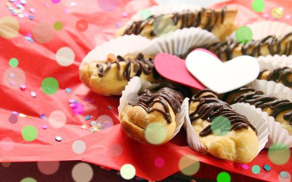 valentine's day concept - sweet love, breakfast for lover: eclairs and hearts on red festive background with copy space