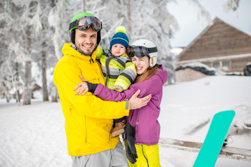 Portrait of a happy family with baby boy standing in winter spots clothes outdoors during the winter vacations