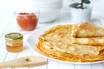 Thin russian pancakes on a plate on white wooden table. Shrovetide. Healthy breakfast concept. Close up.