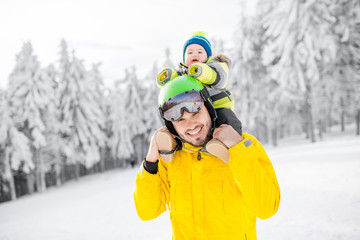 Portrait of a happy father with baby boy standing in winter spots clothes outdoors during the winter vacations