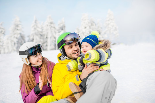 Portrait of a happy family with baby boy during the winter vacations on the beautiful snow-covered mountains
