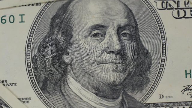 Hundred dollar bills. Portrait of Benjamin Franklin close-up. Macro photography of banknotes. The motion camera slider.