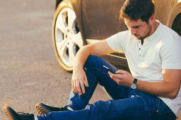Car and smartphone app concept - man texting sms on phone. Driving young male adult using apps for...