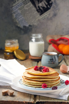 Photo of delicious pancakes with berries and honey over wooden tabe