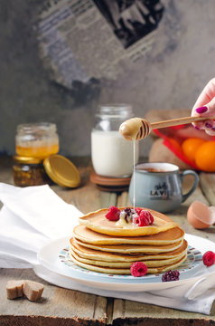 Photo of delicious pancakes with berries and honey over wooden tabe