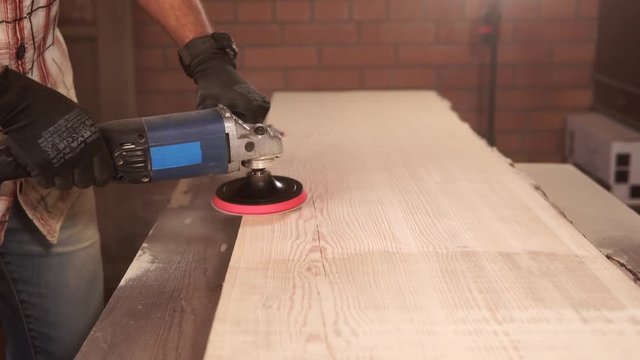 close up shot of a man's hands, who works with an electric drill with a nozzle for polishing a wooden surface, a carpenter working in his workshop to fix and create furniture