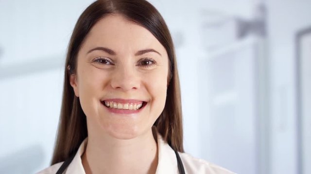 Portrait of smiling confident professional female doctor with stethoscope standing in hospital room. Woman physician at work. Health care concept