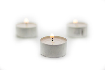 Three burning candles on a white background