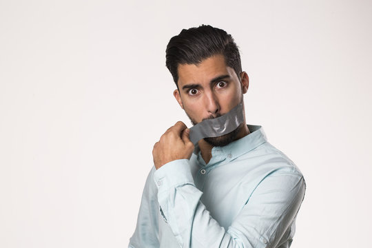 Portrait Of Young Man Removing Tape From His Mouth , Breaking The Silence