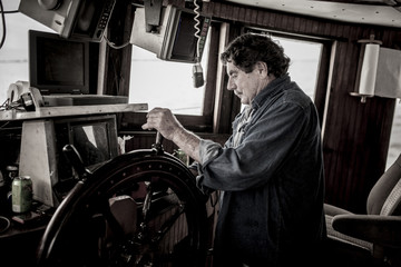 Ships captain at the wheel of a commercial fishing vessel. © Wollwerth Imagery