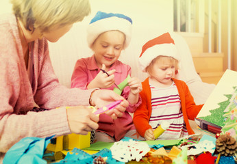 woman helping  two girls to make decoration for Xmas