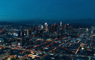 Aerial view of Downtown Los Angeles at twilight with young woman holding out a smartphone in her...