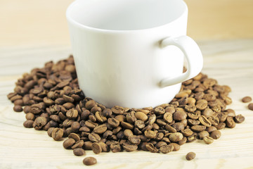 White cup full of coffee beans on Roasted Coffee Beans and wood background, top view