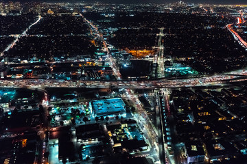 Aerial view of a massive highway in Los Angeles, CA at night with young woman holding out a smartphone in her hand