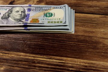 Stack of one hundred dollars bills on wooden desk