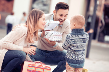 Happy family with little son and shopping bags in city