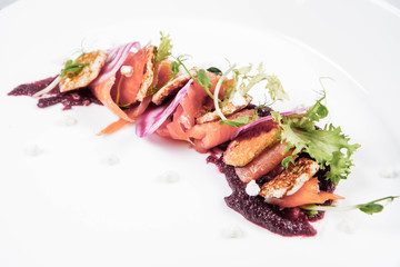 Smoked salmon with roasted beetroots sauce, russian pancakes and horseradish cream served in a restaurant