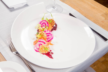 Smoked salmon with roasted beetroots sauce, russian pancakes and horseradish cream served in a restaurant